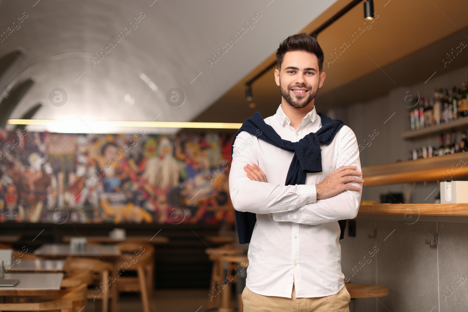 Photo of Young male business owner near counter in his cafe. Space for text