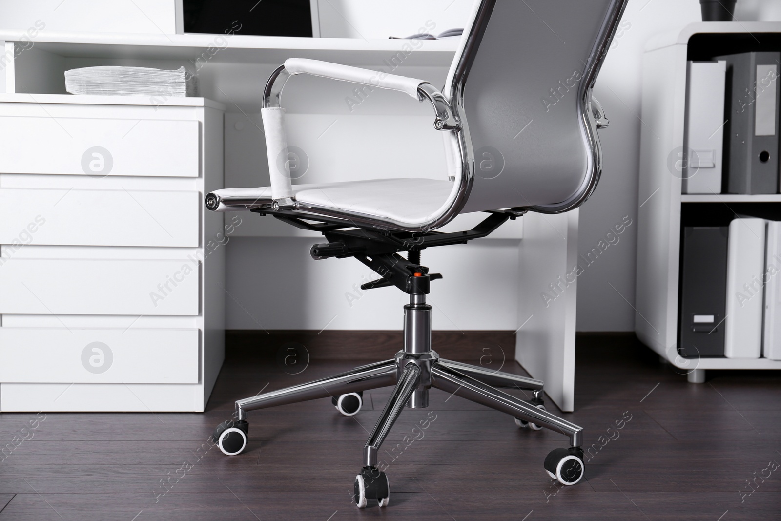 Photo of Comfortable rolling chair near table in modern office