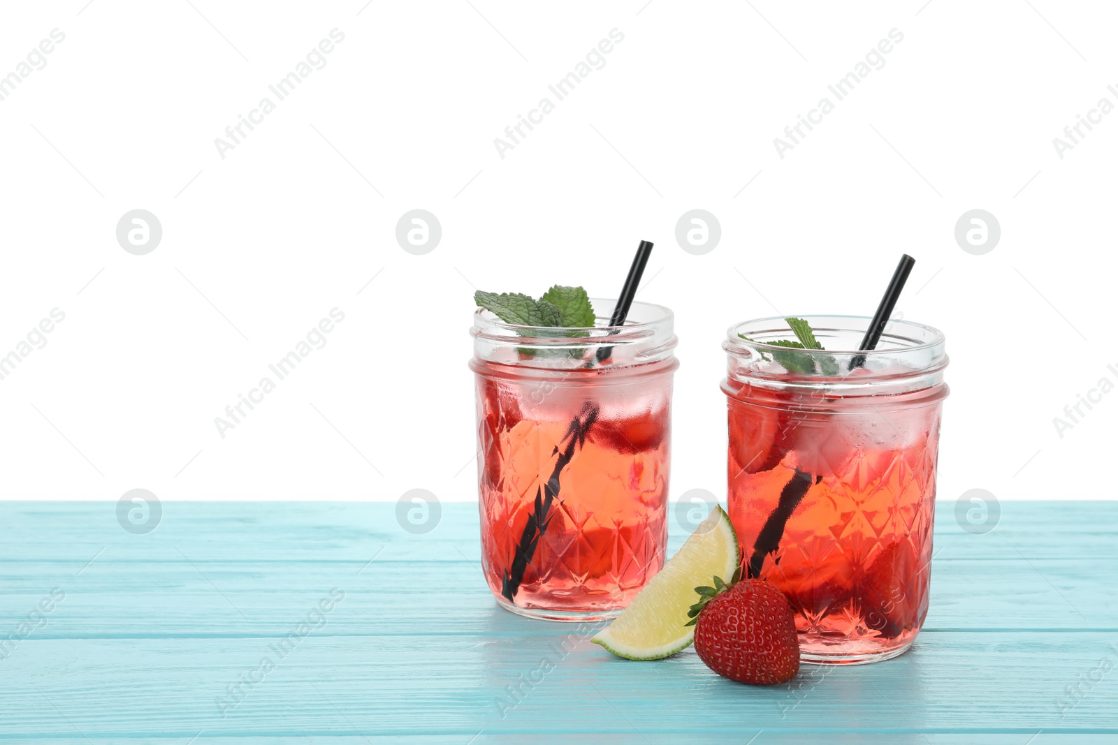 Photo of Refreshing drink with strawberry and lime on light blue wooden table