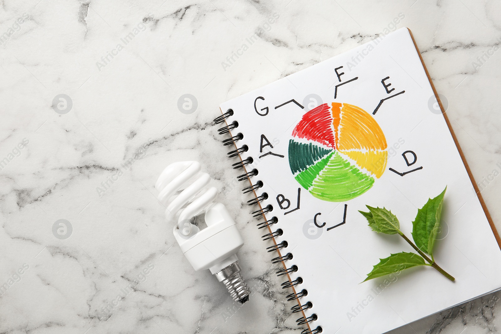 Photo of Flat lay composition with energy efficiency rating chart and fluorescent light bulb on white marble background. Space for text