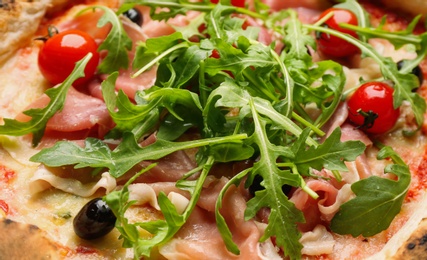 Tasty pizza with meat and arugula as background, closeup view