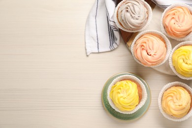 Photo of Tasty colorful cupcakes on white wooden table, flat lay. Space for text