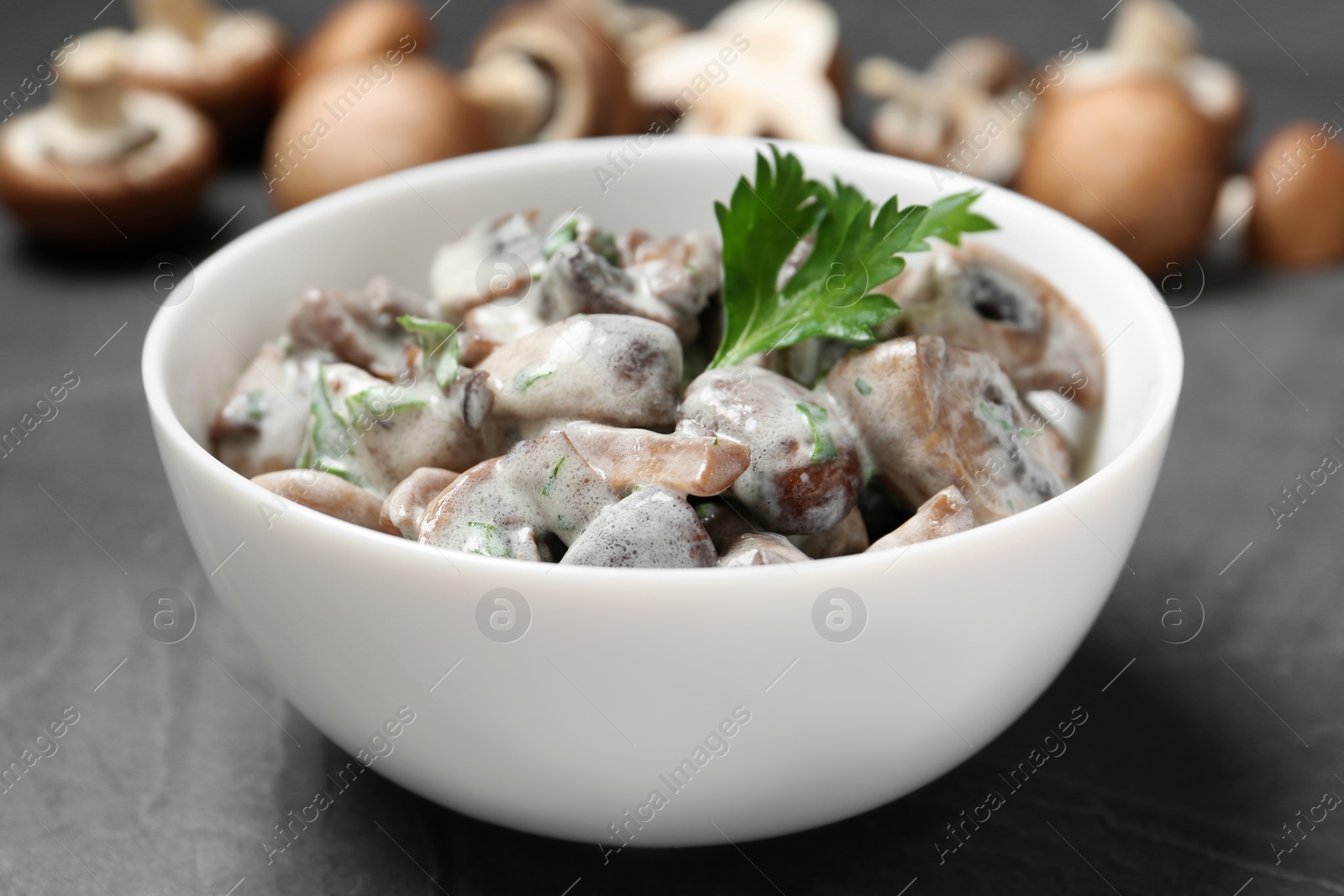 Photo of Bowl of fried mushrooms with sauce on table, closeup