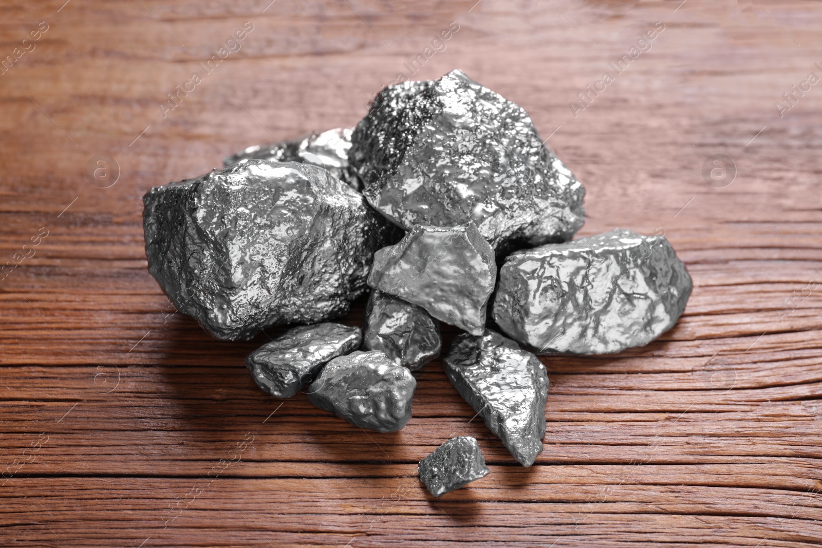 Photo of Pile of silver nuggets on wooden table, closeup