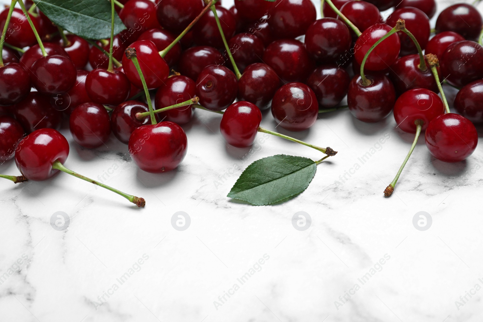 Photo of Sweet juicy cherries on white marble table, closeup