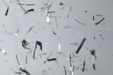 Photo of Shiny silver confetti falling down on light grey background