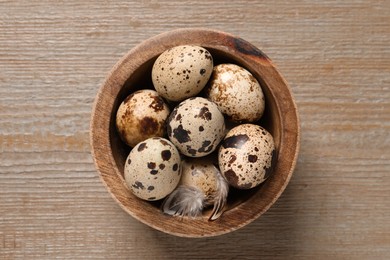 Photo of Bowl with quail eggs on wooden table, top view