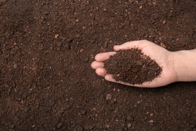 Photo of Woman holding pile of soil above ground, top view. Space for text