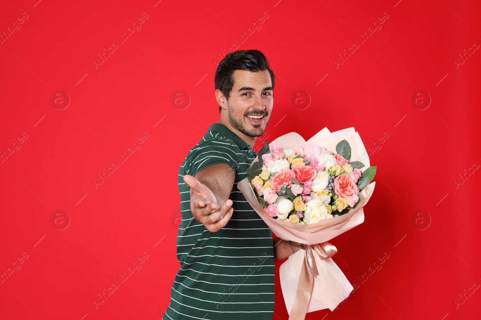 Photo of Young handsome man with beautiful flower bouquet on red background