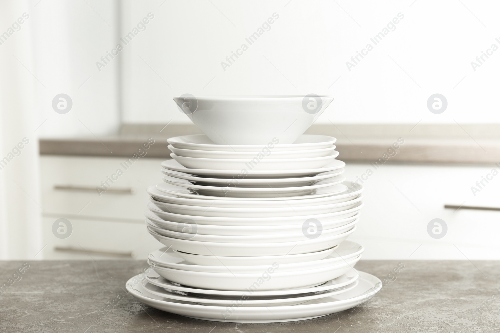 Photo of Stack of clean plates on marble table in kitchen