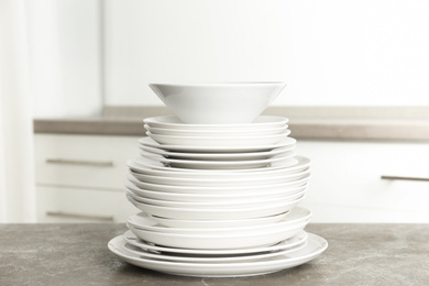 Photo of Stack of clean plates on marble table in kitchen