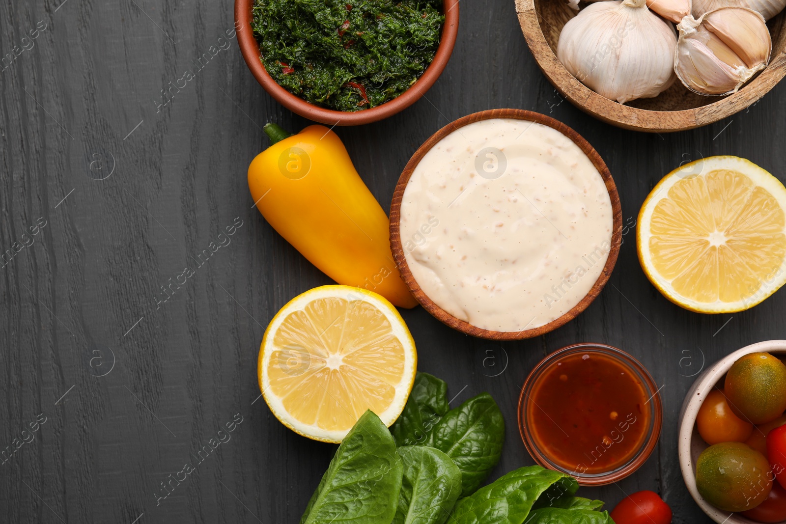 Photo of Different fresh marinades in bowls and ingredients on grey wooden table, flat lay. Space for text