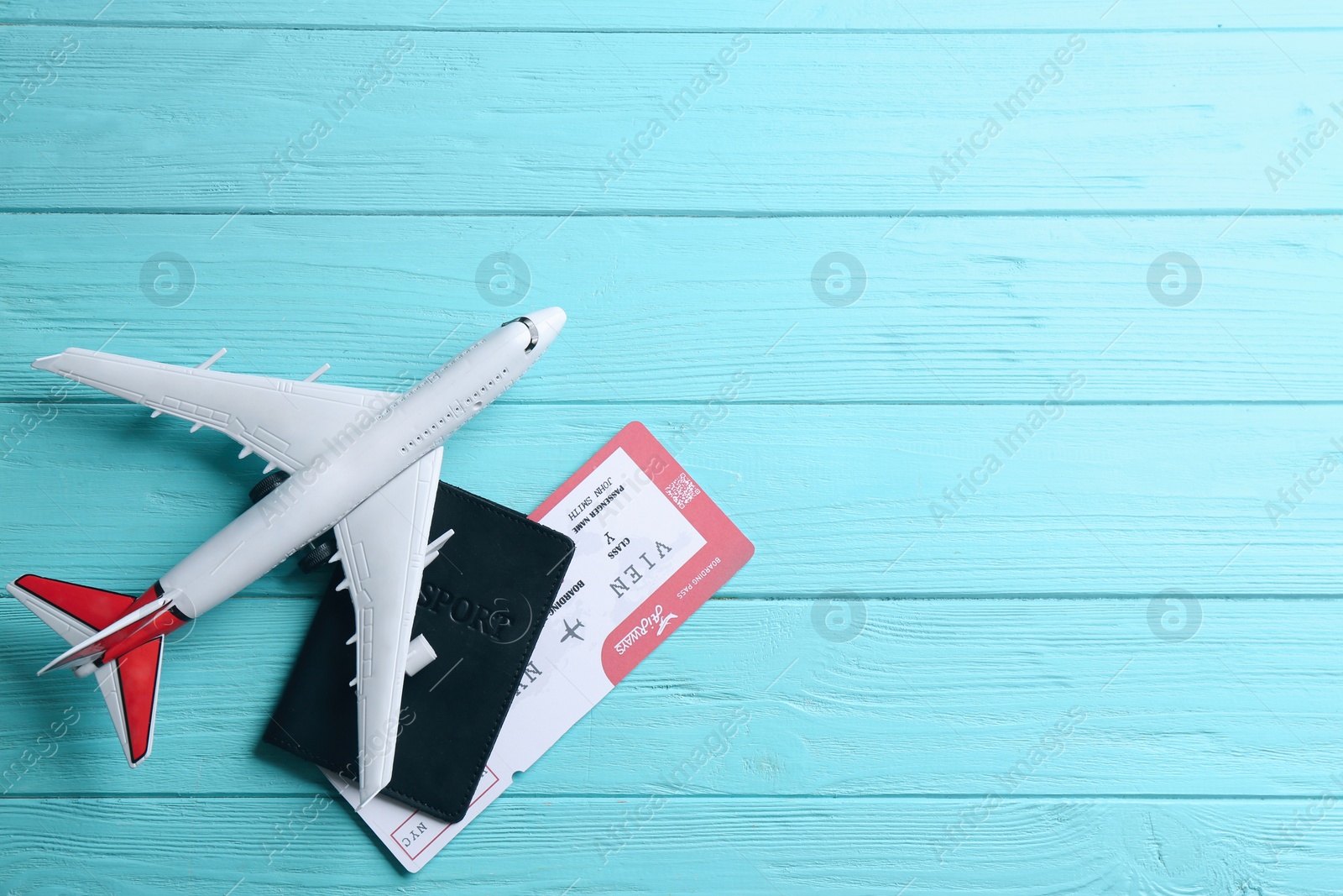 Photo of Toy airplane and passport with ticket on light blue wooden background, flat lay. Space for text