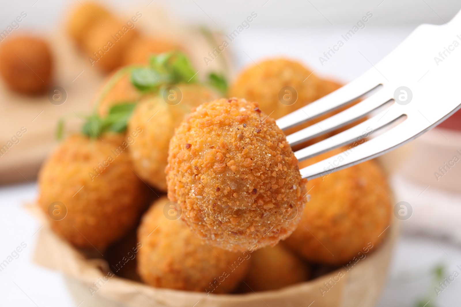 Photo of Taking delicious fried tofu ball with fork from bowl, closeup