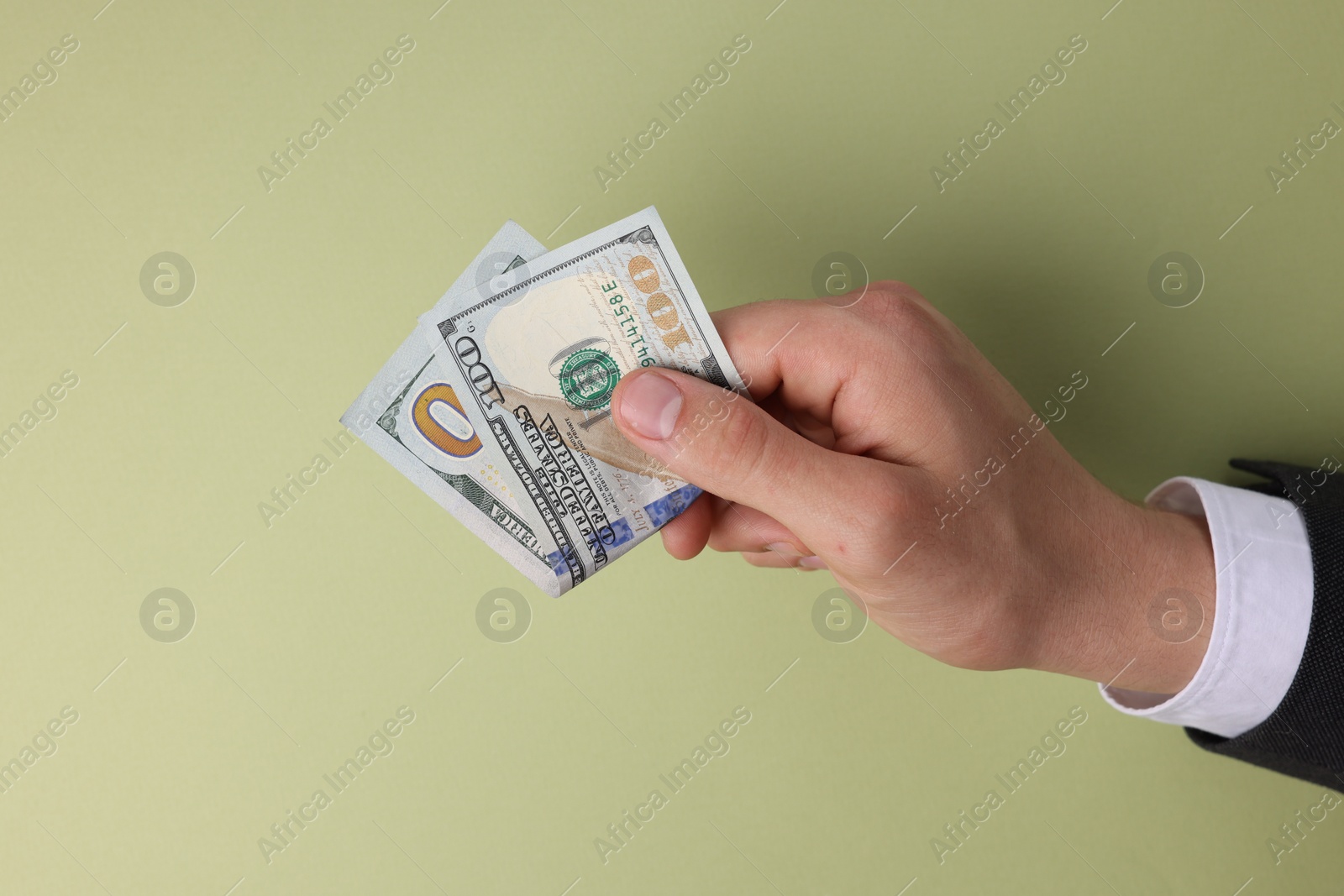 Photo of Money exchange. Man holding dollar banknotes on olive background, top view