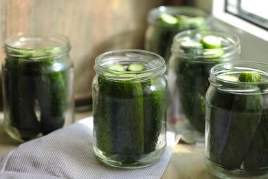Photo of Glass jars with fresh cucumbers on table, closeup. Canning vegetables