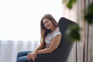 Photo of Young woman resting in armchair at home