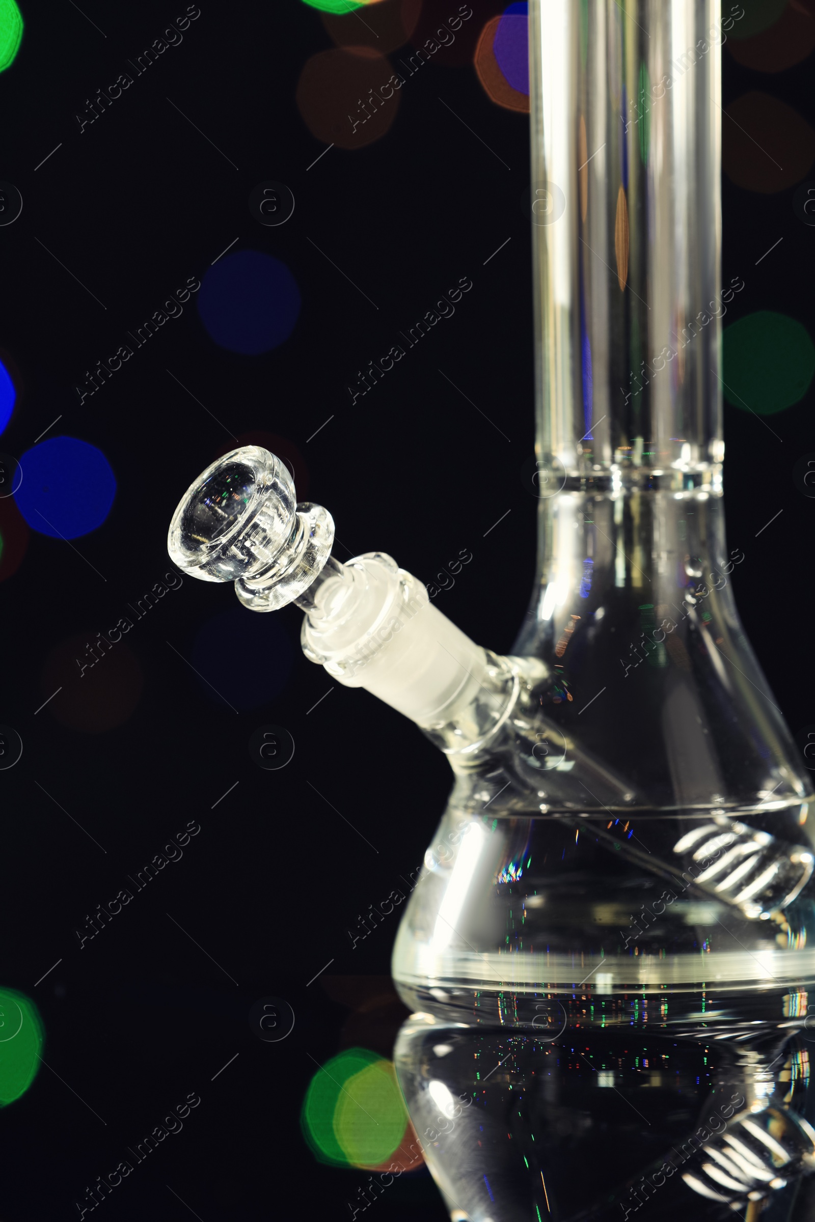 Photo of Closeup view of glass bong against blurred lights. Smoking device