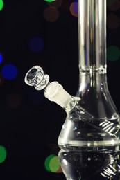 Photo of Closeup view of glass bong against blurred lights. Smoking device