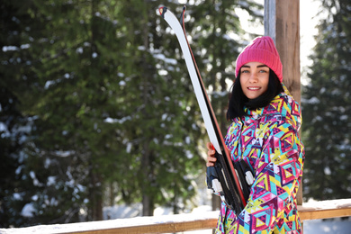 Young woman with ski wearing winter sport clothes in forest. Space for text
