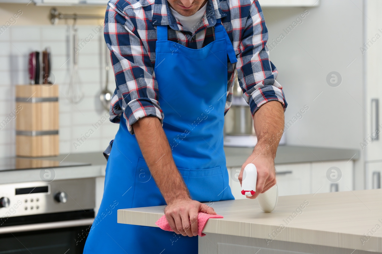 Photo of Man cleaning table with rag in kitchen, closeup