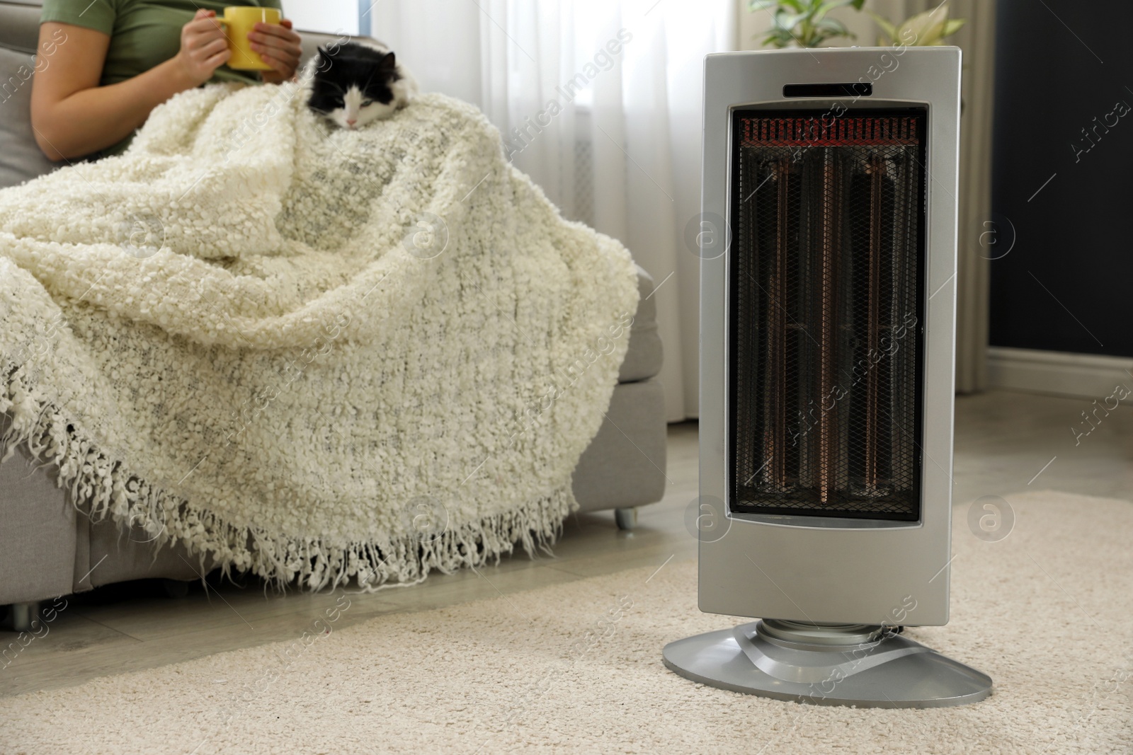 Photo of Woman with cat at home, focus on electric ultrared heater, closeup