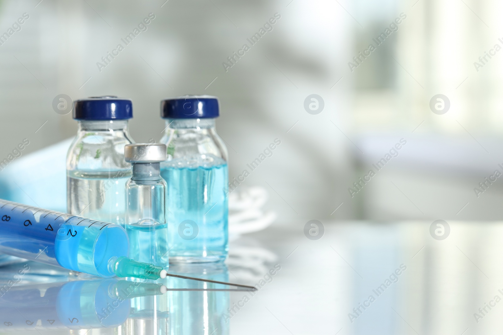 Photo of Glass vials, syringe and medical masks on white table, closeup. Space for text