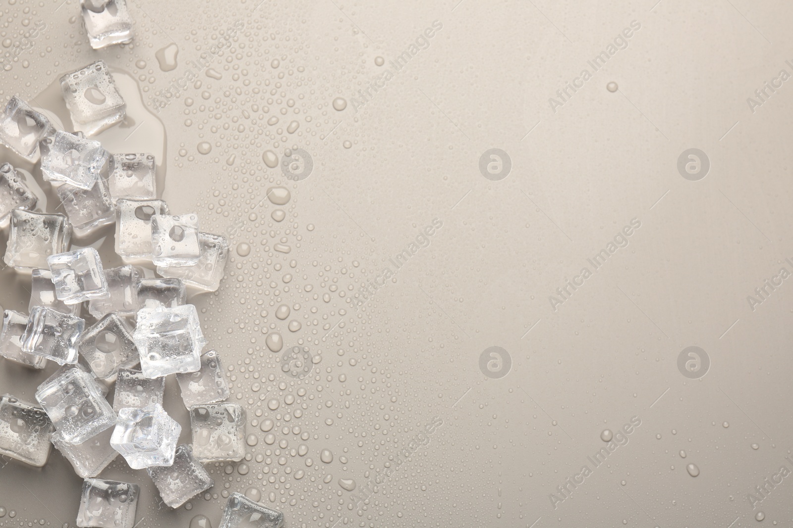 Photo of Melting ice cubes and water drops on light grey background, flat lay. Space for text