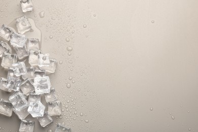 Photo of Melting ice cubes and water drops on light grey background, flat lay. Space for text