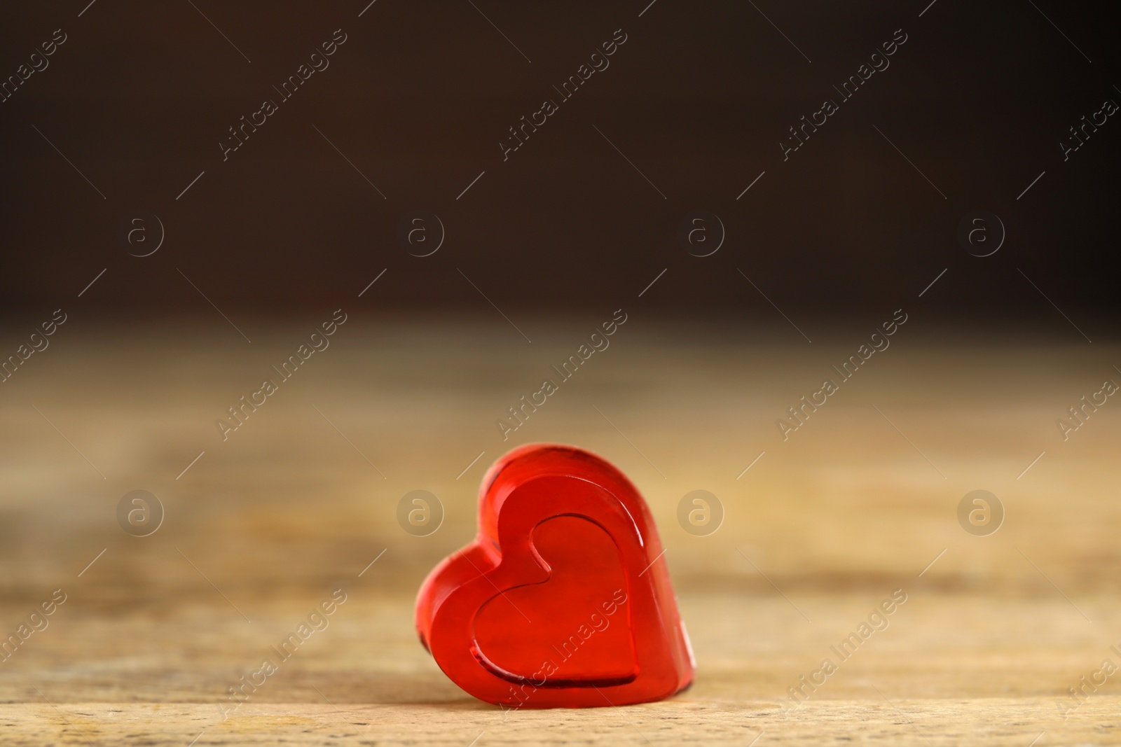 Photo of Sweet heart shaped jelly candy on wooden table, space for text