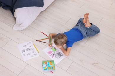 Photo of Little boy coloring on warm floor at home, above view. Heating system