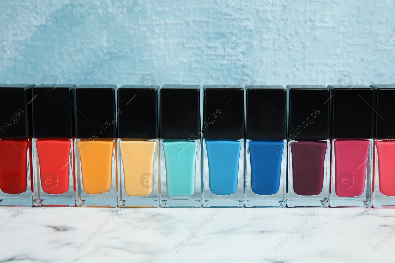 Photo of Bright nail polishes on table against color background