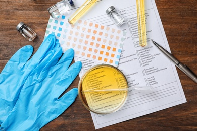 Photo of Flat lay composition with laboratory equipment and urine samples on wooden background. Urology concept