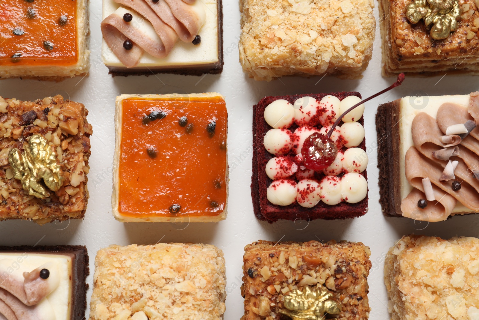 Photo of Pieces of different delicious cakes on white table, flat lay