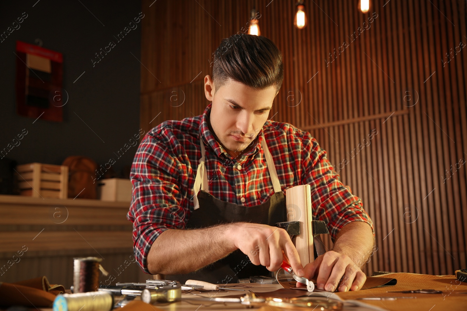 Photo of Man marking leather with roller in workshop