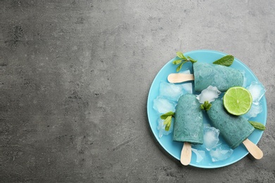 Photo of Plate with delicious spirulina popsicles and lime on grey background, top view. Space for text