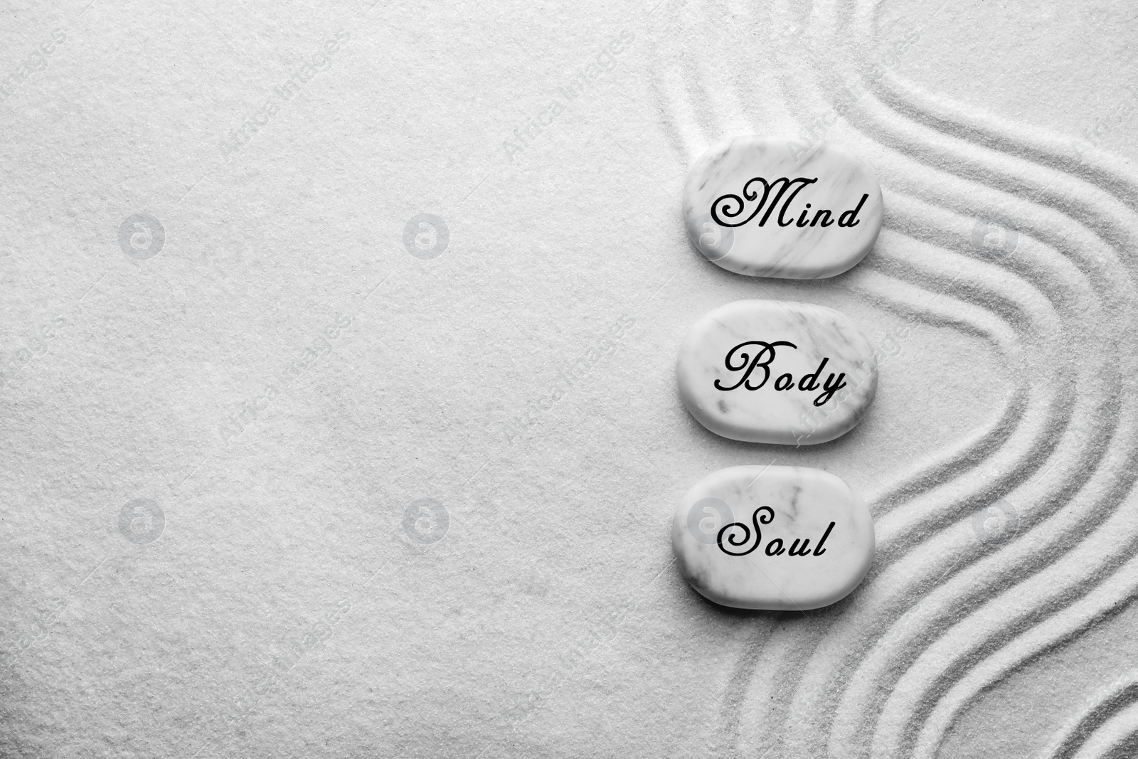 Image of Stones with words Mind, Body, Soul on sand, flat lay. Zen and harmony 