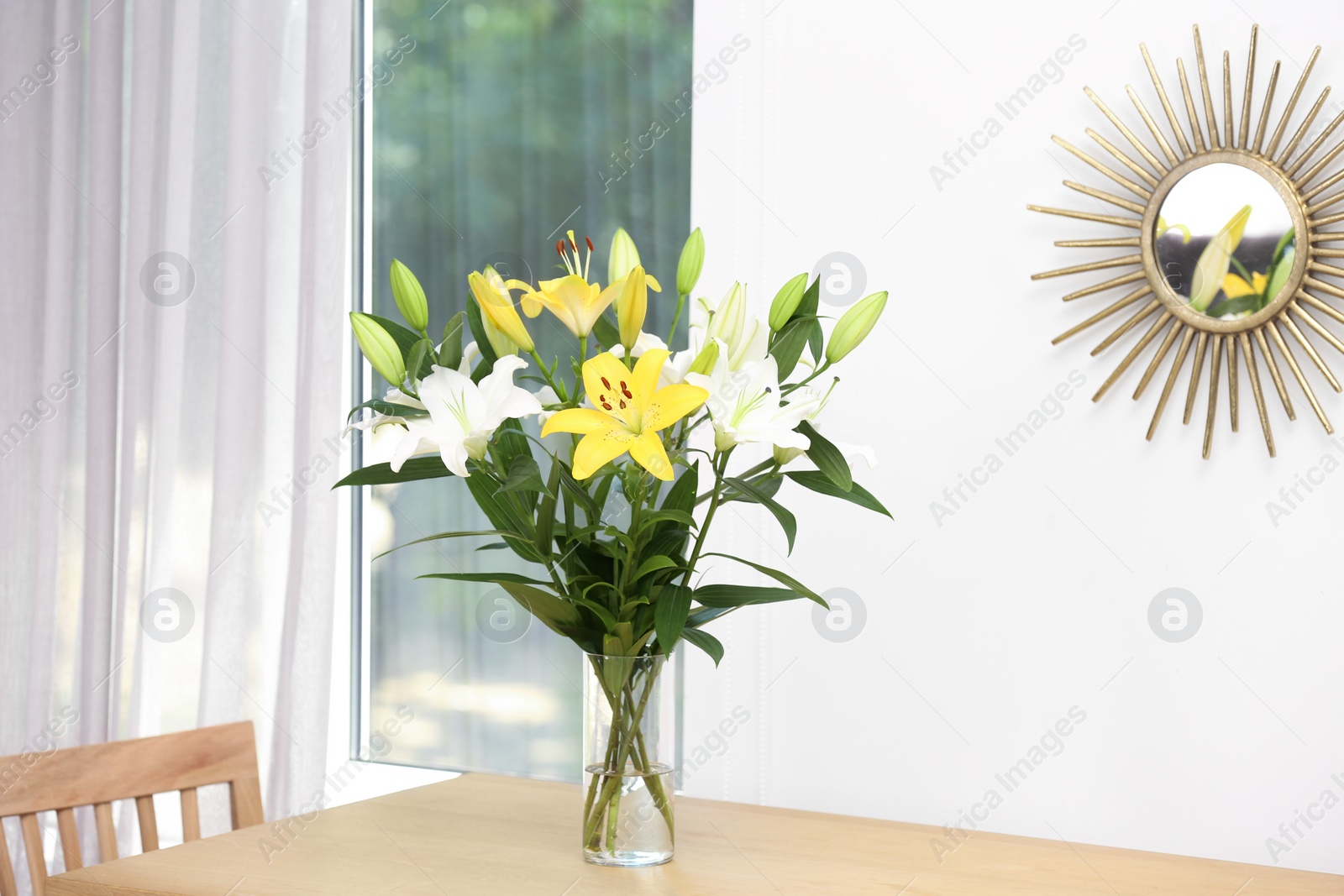 Photo of Vase with bouquet of beautiful lilies on wooden table indoors