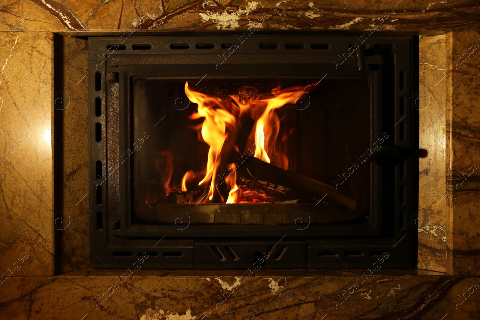 Photo of Fireplace with burning wood in darkness indoors