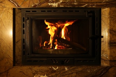 Photo of Fireplace with burning wood in darkness indoors