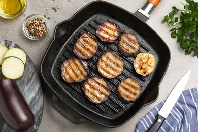 Delicious grilled eggplant slices in pan on grey table, flat lay