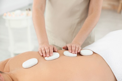 Photo of Man receiving hot stone massage in spa salon, closeup