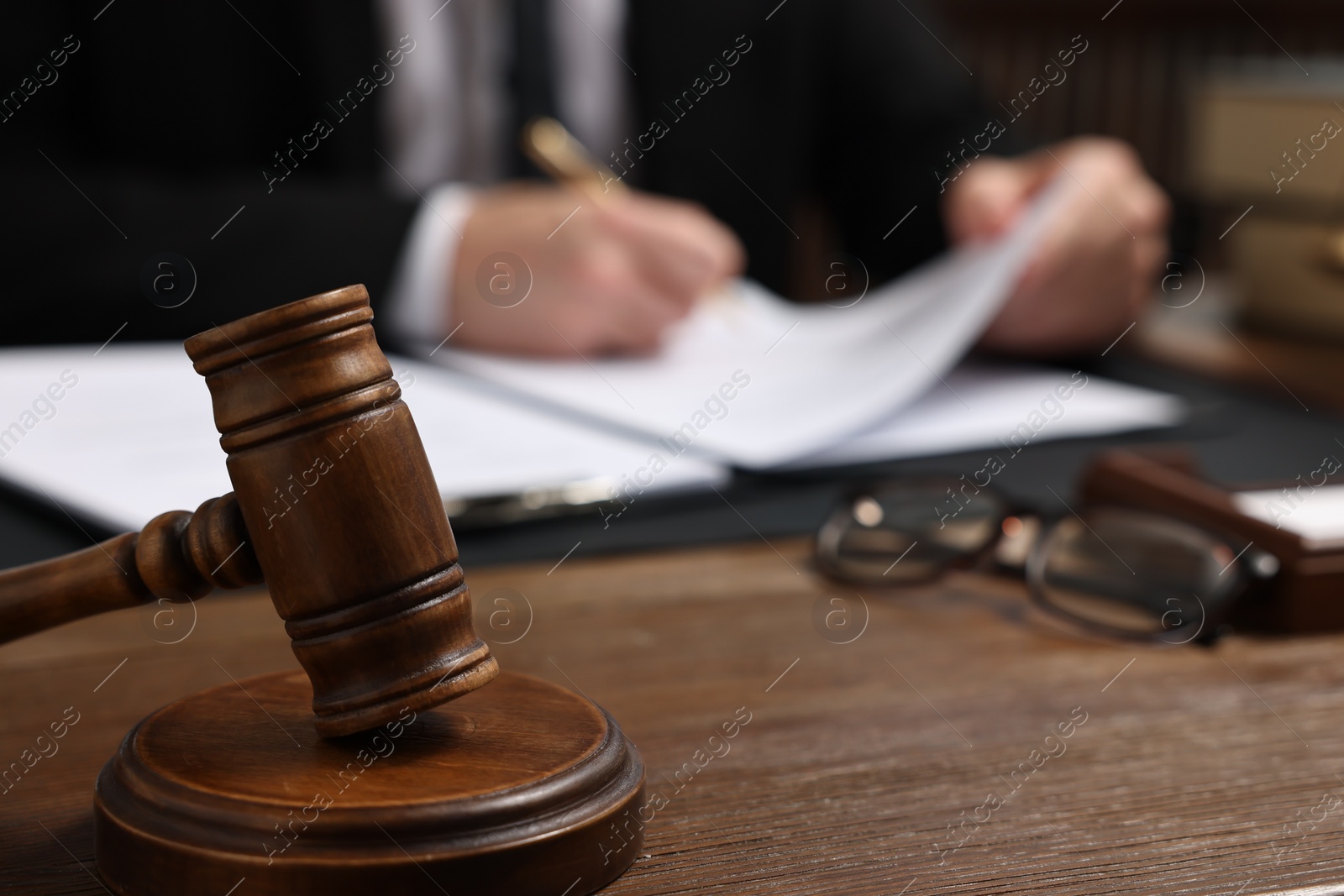 Photo of Lawyer working with documents at wooden table, focus on gavel