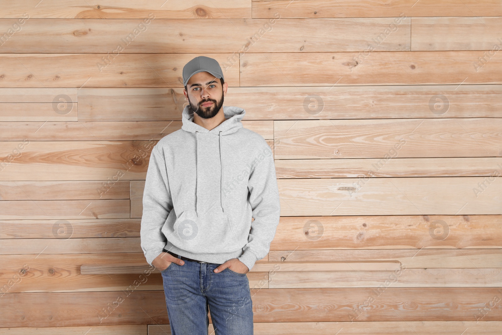 Photo of Portrait of young man in sweater at wooden wall. Mock up for design