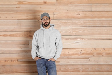 Photo of Portrait of young man in sweater at wooden wall. Mock up for design