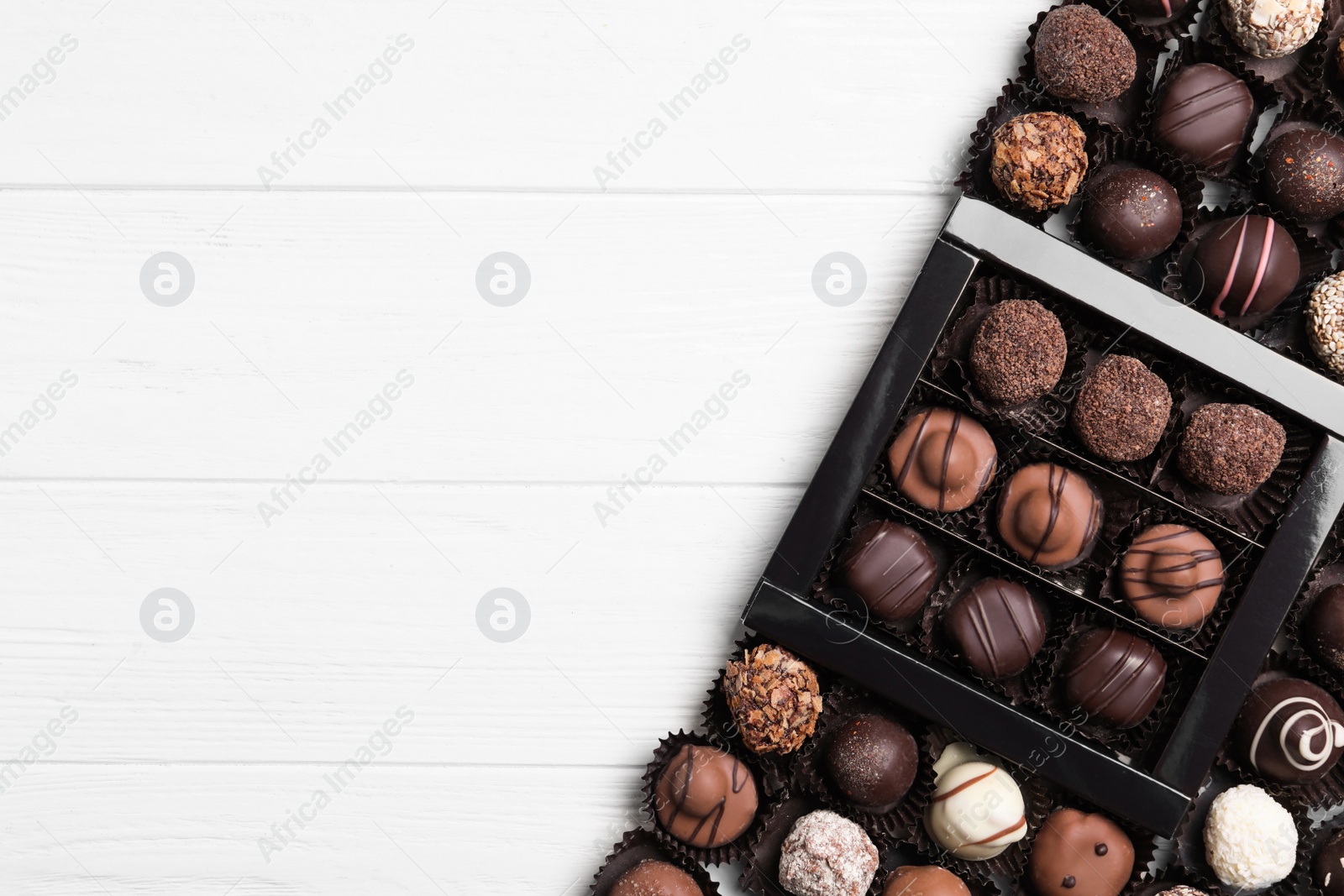 Photo of Different tasty chocolate candies on white wooden table, flat lay. Space for text