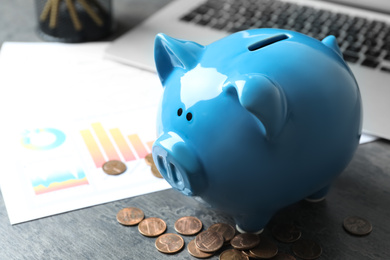 Blue piggy bank and money on grey table, closeup