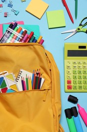 Photo of Backpack with different school stationery on light blue background, flat lay