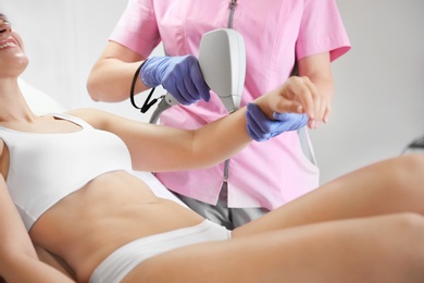 Photo of Young woman undergoing laser epilation procedure in beauty salon