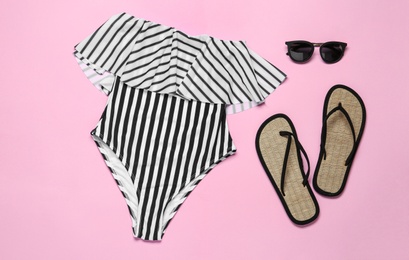 Photo of Flat lay composition with striped swimsuit and beach accessories on pink background